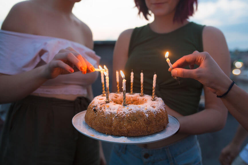 Students lighting candles on a bundt cake sprinkled with icing sugar